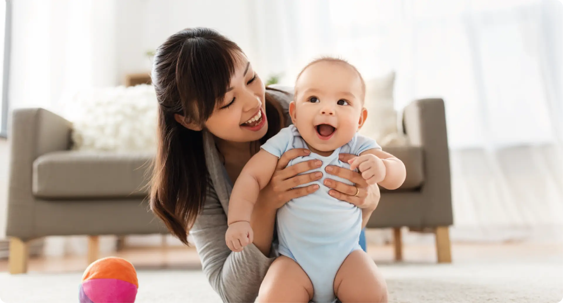 A mother holding and smiling at her baby.